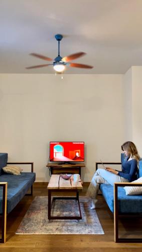 a woman sitting on a couch in a living room at Sava apartment in Novi Sad