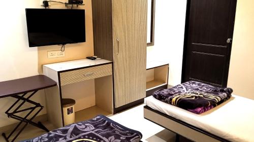 Kleines Zimmer mit einem Schreibtisch und einem TV. in der Unterkunft Hotel RamNiwas in Jālgaon