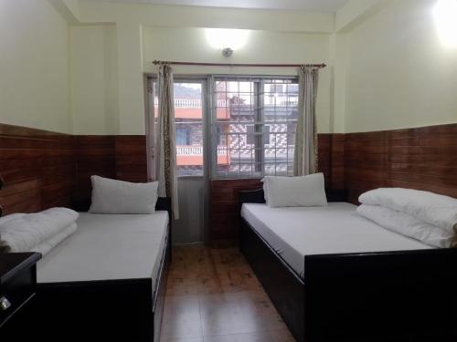 twee bedden in een kamer met een raam bij Memory Guest house in Pokhara
