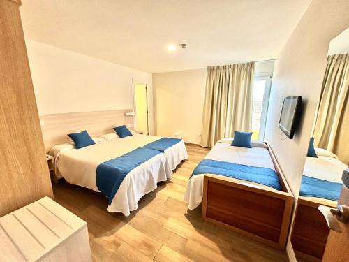a hotel room with two beds and a tv at Bluewater Hotel in Colònia de Sant Jordi