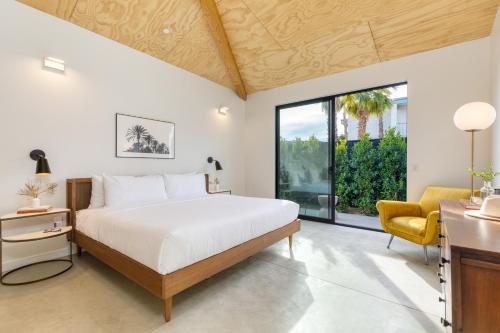ein Schlafzimmer mit einem großen Bett und einem gelben Stuhl in der Unterkunft Blackhaus A B Buyout by AvantStay Sleeps 16 in Palm Springs