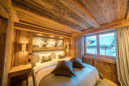 ein Schlafzimmer mit einem Bett in einem Zimmer mit Holzwänden in der Unterkunft Seven Alpina Boutique Hotel in Klosters Serneus