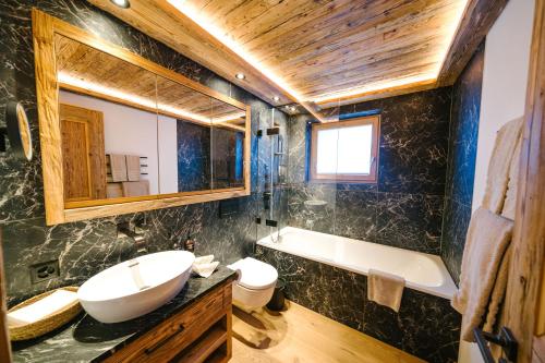 uma casa de banho com um lavatório, uma banheira e um WC. em Seven Alpina Boutique Hotel em Klosters Serneus
