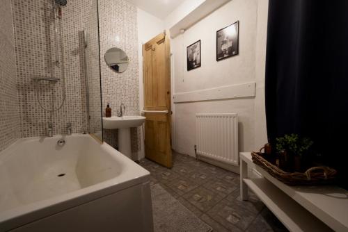 a bathroom with a white tub and a sink at Centrally Located Stylish Flat in Jesmond