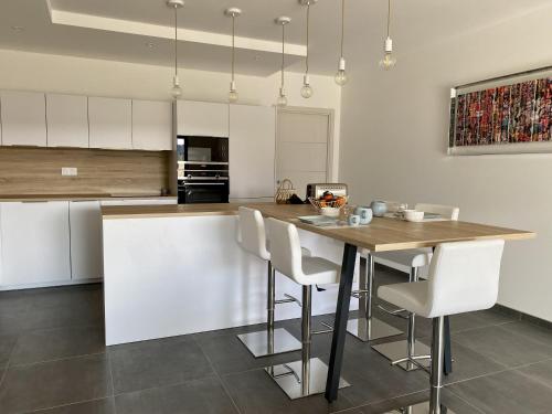 - une cuisine avec une table en bois et des chaises blanches dans l'établissement Domaine d'Arca - Flaubert 06 - 3 chambres - rez de chaussée, à Porto-Vecchio