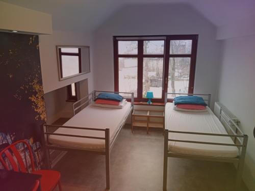 a room with two beds and a window at Łódzki Pałacyk - Pokoje hostelowe in Łódź