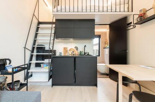 a kitchen with black cabinets and a spiral staircase at KODA Edam in Edam