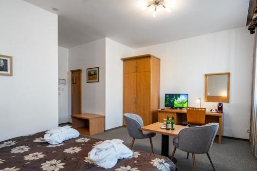 a hotel room with a bed and a desk and a table at Hotel Galant Mikulov in Mikulov