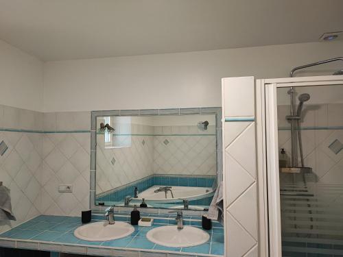 ein Badezimmer mit zwei Waschbecken und einer Badewanne im Spiegel in der Unterkunft Gite Meuz' Friendly 