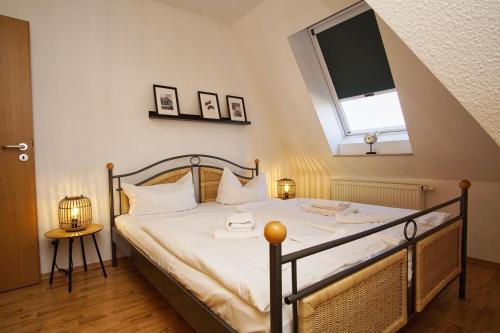 - une chambre avec un lit doté de draps blancs et une fenêtre dans l'établissement Hafenhäuser Breege FeWo 06 - Balkon, Meerblick, à Breege