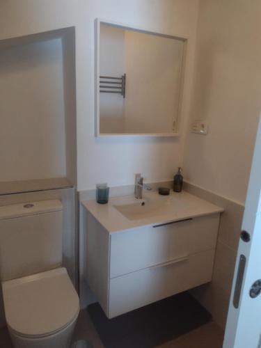 Un baño con lavabo, inodoro y espejo. en Ocle, en Colunga