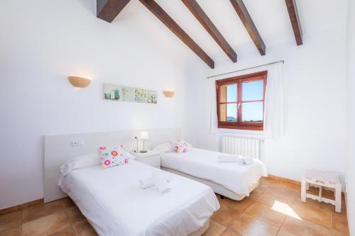 2 camas en una habitación blanca con ventana en Finca Na Maians, un entorno idílico en Artà, en Canyamel
