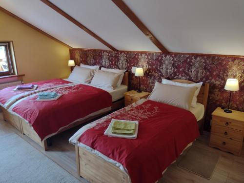 a bedroom with two beds with red sheets at L' Angolo Divino in Lądek-Zdrój