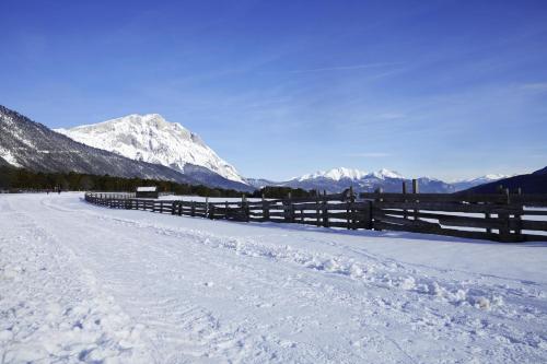 a snow covered road with a fence and mountains at Haus Miriam in Mieming
