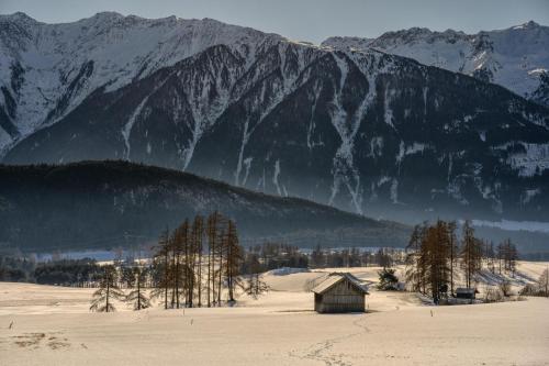 a barn in a snowy field with mountains in the background at Haus Miriam in Mieming
