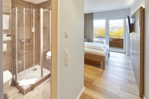 a bathroom with a shower and a bedroom with a bed at Hotel Sonneck in Knüllwald