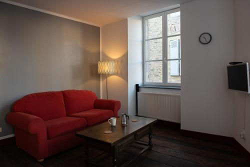 Sala de estar con silla roja y mesa de centro en L´Étape du Coin, en Saint-Yrieix-la-Perche