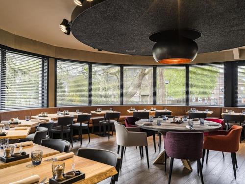 a restaurant with tables and chairs and windows at 2-Bedroom Apt Above Venti Restaurant Near Xpo in Zwevegem