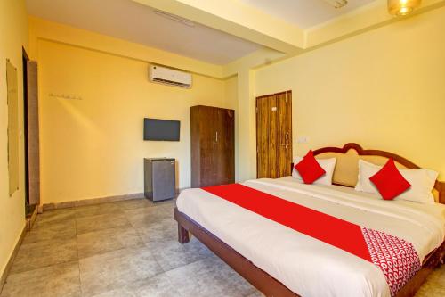een slaapkamer met een groot bed met rode kussens bij OYO Shruti Guest House in Goa