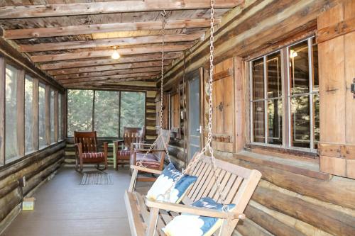 un porche con 2 sillas colgantes y una mesa en Russell Cabin, en Logan