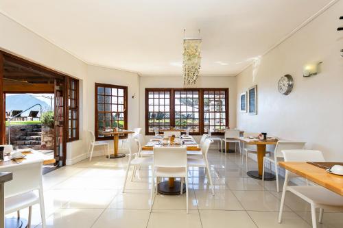 een restaurant met witte stoelen, tafels en ramen bij Harbour House Hotel - Le Paradis Apartments in Hermanus