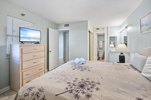a bedroom with a bed with a television and a dresser at Perdido Sun Resort 704 By Pkrm in Pensacola