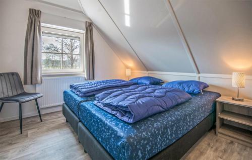 a bedroom with a bed with blue pillows and a window at Amazing Home In Den Ham With Sauna in Den Ham