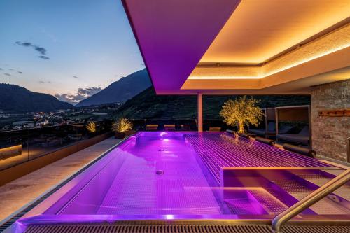 a swimming pool with purple lights on top of a building at Nutzhof - Mediterran Flair Hotel in Lagundo