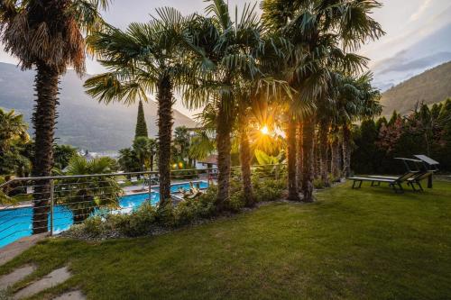 a resort with a pool and palm trees at Nutzhof - Mediterran Flair Hotel in Lagundo