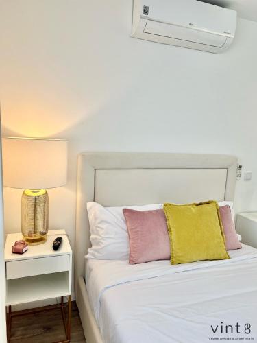 a bedroom with a white bed with pink and yellow pillows at Casa do Golfe by VinteOito in Amarante