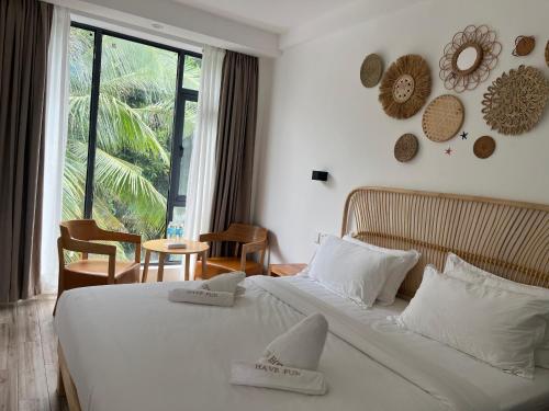 a bedroom with a large white bed and a window at Fun Hotel in Panglao