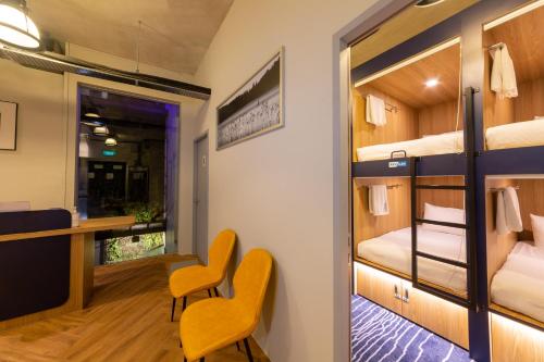 a room with bunk beds and a desk and chairs at Bluewaters Pods 11 North Canal Road in Singapore