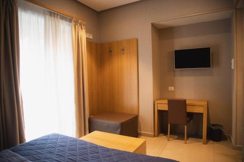 a bedroom with a bed and a desk with a monitor at Airone Hotel in Naples
