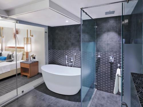 The Cliff Resort & Spa, Panchgani في بانتشجانى: حمام مع حوض استحمام وغرفة نوم
