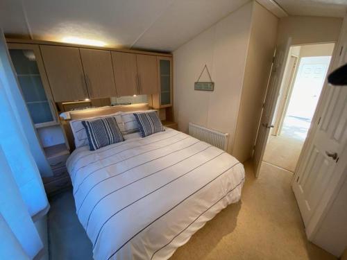 a bedroom with a large white bed with blue pillows at Ocean View Sunbeach in Llwyngwril