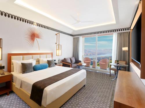 The Cliff Resort & Spa, Panchgani في بانتشجانى: غرفة فندقية بسرير ونافذة كبيرة