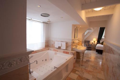 a large bathroom with a large tub and a sink at Hotel Schimmelpenninck Huys in Groningen
