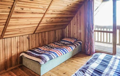 a bed in a room with a wooden wall at Amazing Home In Mielno With Kitchen in Mielno