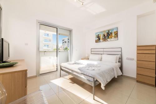 a white bedroom with a bed and a tv at Silver Sands Penthouse in Protaras