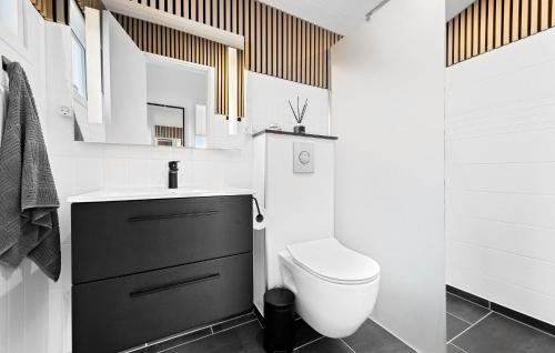 Baño blanco con aseo y lavamanos en Gorgeous Home In Dronningmlle With Kitchen, en Dronningmølle