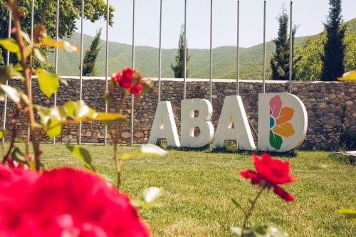 a sign with flowers in front of a garden at Art Hotel by ABAD Guest in Sheki
