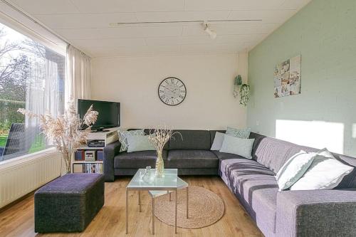 a living room with a couch and a clock on the wall at Duinland 251 - Park Duinland Sint Maartenszee in Sint Maartensvlotbrug