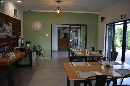 a restaurant with wooden tables and green walls at Symponia Guesthouse in Ghanzi