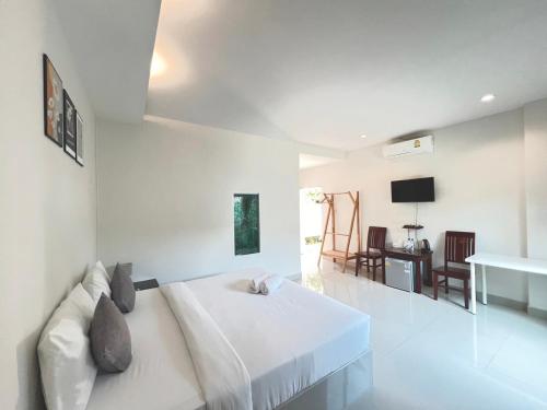 a white bedroom with a bed and a table at On Green Resort in Ban Huai Sua