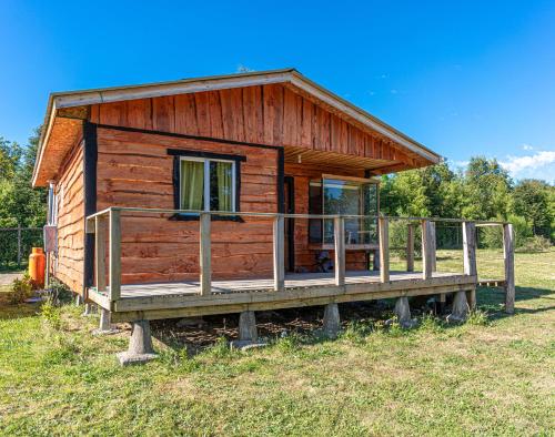 a small wooden cabin with a porch on a field at Cabañas Estrella del Sur in Puerto Varas