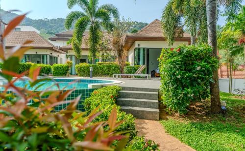 a house with a swimming pool and palm trees at Phuket Boutique Pool Villa-80 in Rawai Beach