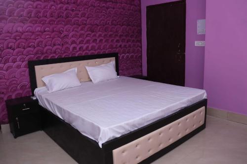 a bedroom with a bed with a purple wall at SPOT ON Gajadhar Rest House in Deoghar