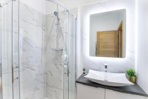a white bathroom with a sink and a shower at The Residence At The Lawrence Apartments in York