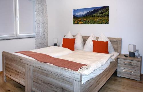 a bedroom with a large wooden bed with orange pillows at Schindelbacherhof in Spielberg