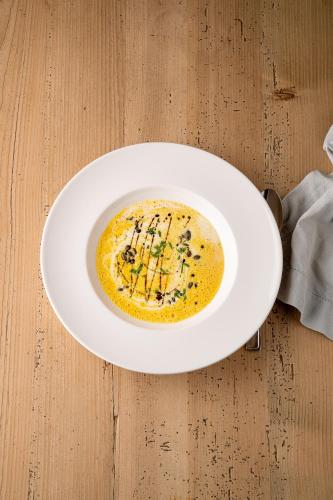 a white plate on a table with a bowl of soup at Schlegelhof in Kirchzarten